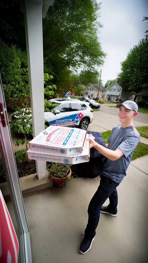 A medium close-up shot of a friendly male pizza de...